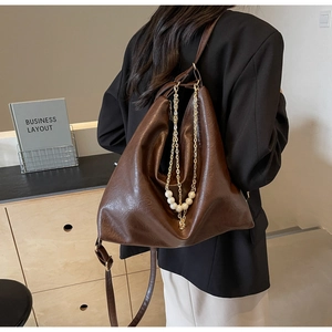 Detail of a dark brown PU leather tote bag featuring gold chains and white pearl accents