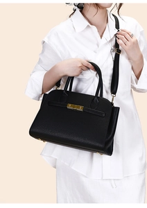 Close-up of black litchi pattern tote bag featuring gold twist lock and leather strap