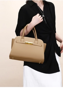 Detail showing litchi grain texture and gold buckle on a stylish camel tote bag