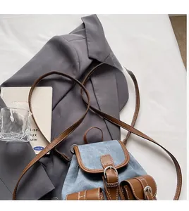Detail of light blue denim mini backpack with brown leather straps and contrast stitching