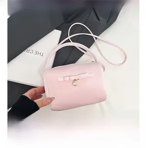 Rosa Zylindertasche im Detail mit Schleife, Perle und Smartphone-Größenvergleich