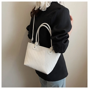 Détail du sac cabas tressé blanc montrant la texture chevrons et le nœud de poignée