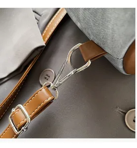 Detail of durable silver spring hook and brown leather strap with fine white stitching