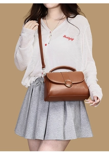 Detailed view of brown underarm bag with gold metal buckle and leather shoulder strap
