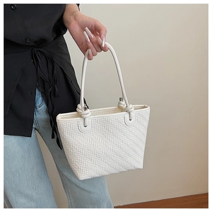Détail d'un sac bandoulière blanc tressé montrant la texture cuir et boucle en métal