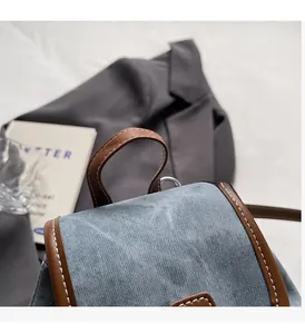 Detailed view of denim backpack with brown leather trim and premium stitching details