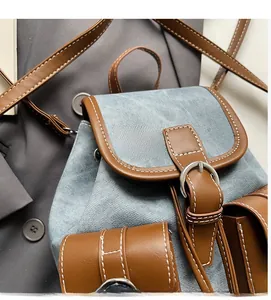 Detailed close-up of denim backpack with brown leather trim and contrast stitching