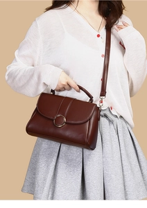 Detailed macro view of brown PU leather bag featuring a gold circular metal buckle and strap