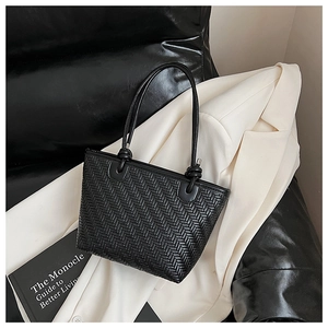 Détail du sac tissé noir avec texture en V et bandoulière à nœud sur un blazer blanc