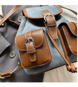 Detail of denim and leather contrast backpack with metal buckle and functional pockets