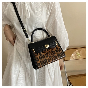 Borsa Kelly leopardata con dettagli dorati indossata da modella in abito di pizzo bianco