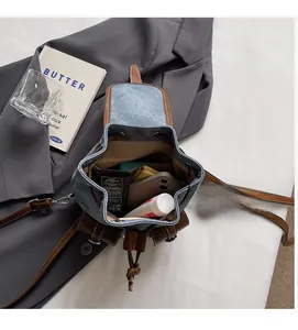 Detail view of denim backpack interior storage showing phone, wallet, and cosmetics inside