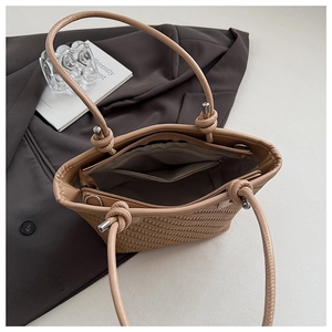 Vue détaillée du sac cabas beige tressé avec compartiment zippé et finitions en nœuds