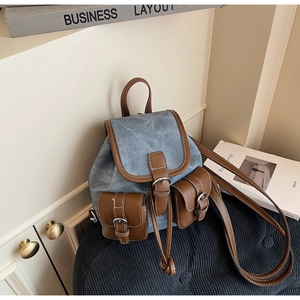 Detail of vintage denim backpack with brown leather trim and two front buckle pockets