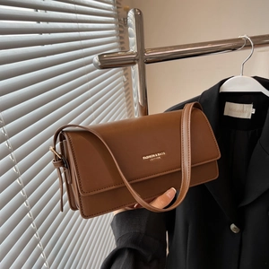 Brown leather baguette bag with fashion lettering shown in a stylish hand-held pose
