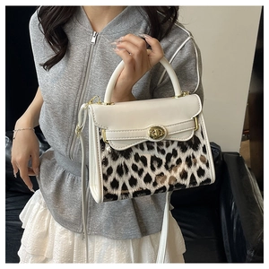 Dettaglio di una borsa in pelle bianca e leopardata con chiusura dorata e manico