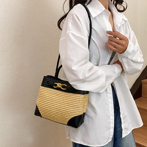 Straw tote bag with black leather trim and gold twist lock in a lifestyle setting