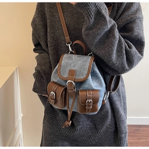 Close-up of vintage blue denim backpack with brown leather trim and metal buckles