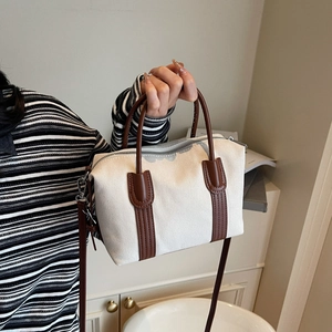 Sac Boston rétro en toile avec garniture en cuir marron présenté à la main dans un intérieur