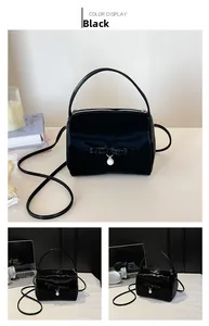 Details der schwarzen Handtasche mit eleganter Schleife, Perlenanhänger und Glanz