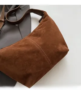 Gros plan détaillé du sac hobo en daim marron avec double surpiqûre et large bandoulière