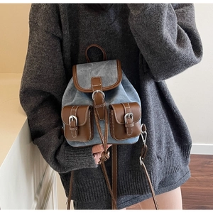 Detail view of denim backpack showing vintage suede texture and white contrast stitching