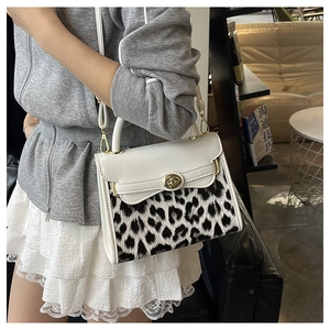 Dettaglio del patchwork leopardato e chiusura a girello dorata su borsa in pelle bianca
