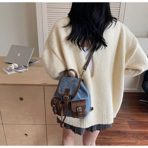 Detailed back view of mini denim backpack with brown leather trim and buckle pockets