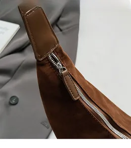 Détail de la fermeture éclair argentée et tirette en cuir brun sur sac en daim rétro
