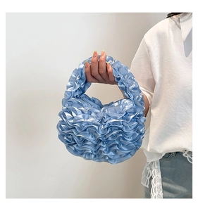 Close-up of light blue pleated handbag with ruffled satin fabric and petal-like texture
