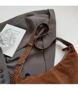 Gros plan détaillé du sac bandoulière en daim marron avec surpiqûres blanches