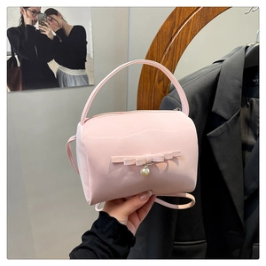 Detailansicht der hellrosa Handtasche mit dekorativer Schleife und Perlenanhänger