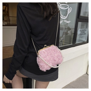 Detail of pink floral handbag with 3D fabric roses, pearl beads, and gold metal clasp
