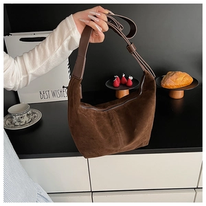Détail du sac hobo en daim marron foncé avec bandoulière réglable et texture mate