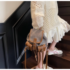 Close-up of vintage canvas backpack with brown leather trim on wooden stairs