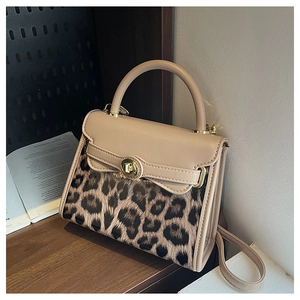 Dettaglio borsa patchwork leopardata con chiusura dorata su un tavolo di legno