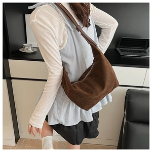 Modèle portant un sac hobo en daim marron foncé avec large bandoulière en cuir pour femme
