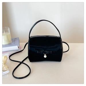 Detail einer schwarzen Satin-Handtasche mit Schleifendekor und Perlenanhänger im Fokus