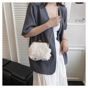 Detail of elegant white lace bag with 3D fabric roses, pearls and gold chain strap