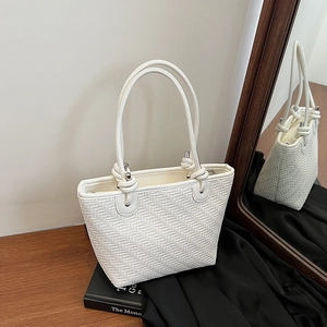 Sac bandoulière blanc tressé avec détails argentés sur une table en bois