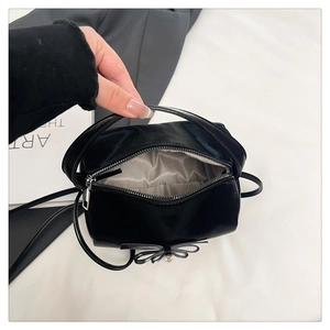 Detailsicht der kleinen schwarzen Handtasche mit Schleife, Perle und Fischgrätfutter