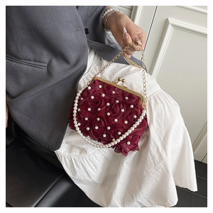 Detailed view of the burgundy 3D floral evening bag featuring pearls and a gold chain strap
