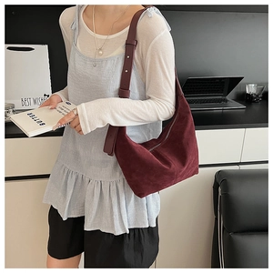 Détail du sac demi-lune en daim bordeaux montrant la texture et la bandoulière ajustable