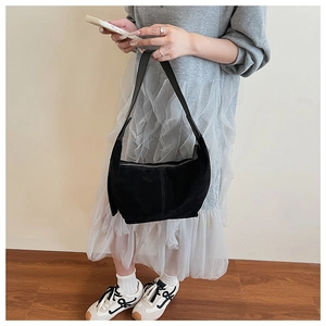 Détail d'un sac demi-lune en daim noir montrant sa texture épaisse et son design minimaliste