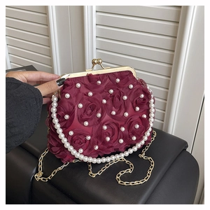Detailed view of burgundy satin rose evening bag with pearls and gold metal chain