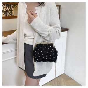 Close-up of black floral lace handbag with pearl handle and metal clasp closure
