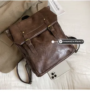 Detailed size comparison of the vintage dark brown backpack next to an iPhone 12
