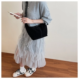 Détail du sac croissant en daim noir avec bandoulière large ajustable sur modèle