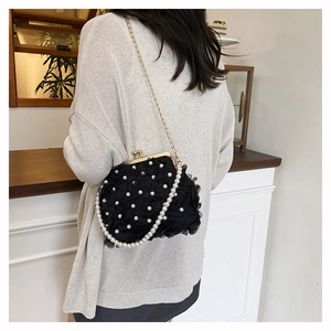 Detail view of black floral evening bag with lace layers and pearl accents