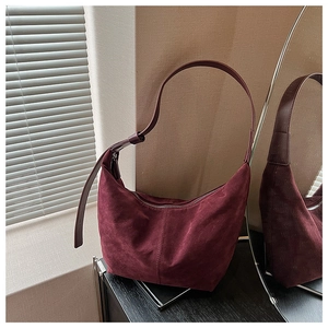 Détail de la texture du sac hobo en daim bordeaux avec bandoulière et vue miroir latérale